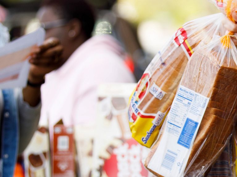 A masked woman takes bread from a cart