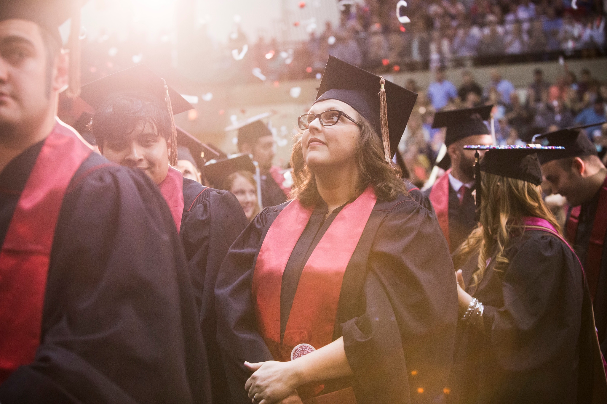 A female student looks at confetti flying down at the 2017 IU East commencement ceremony