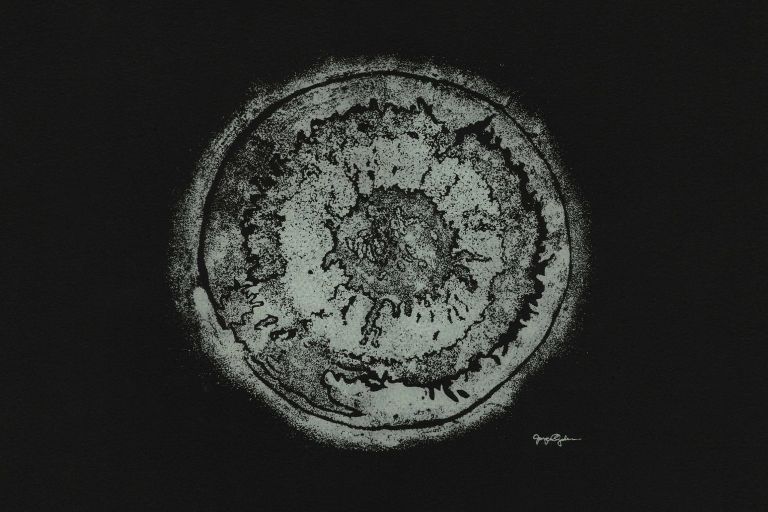 A grayscale circular screenprint with the artist's signature at the bottom right