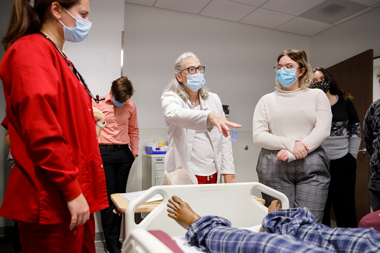 A teacher in a white coat speaks to students