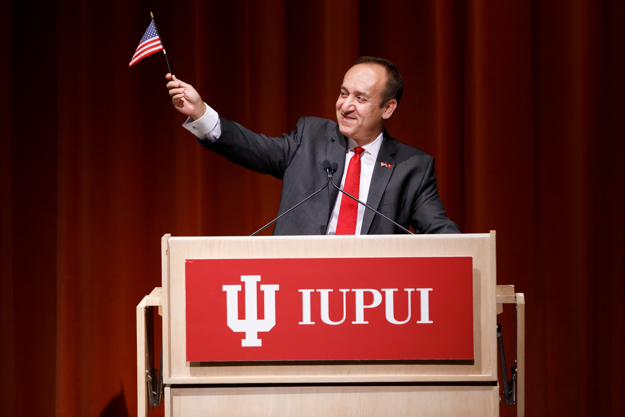 IUPUI Chancellor Nasser Paydar waves a mini American flag at a podium
