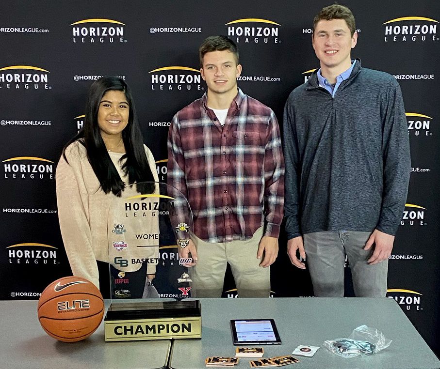 Sports management students stand around a table promoting the Horizon League Tournament