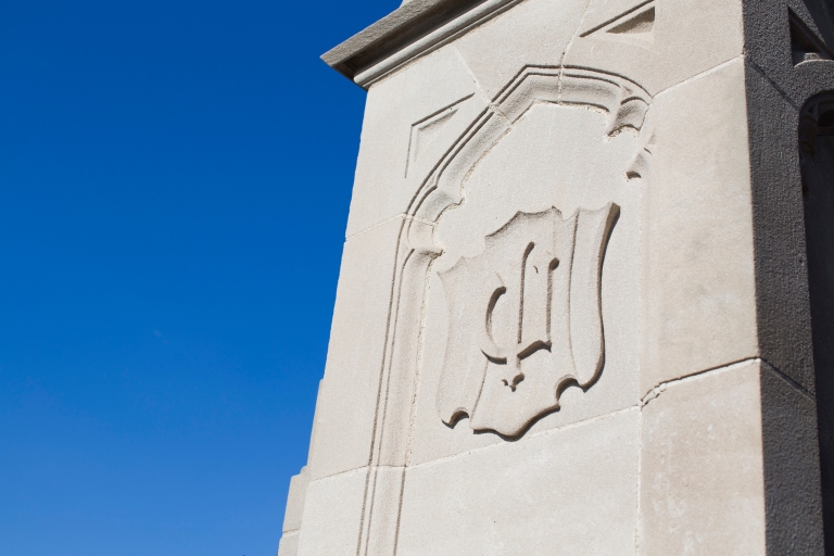Limestone piece of building carved with IU trident against a brilliant blue sky