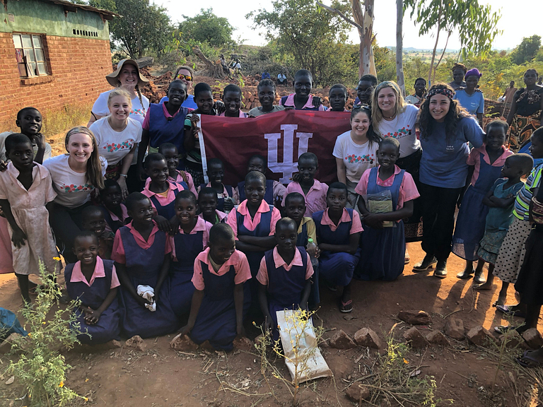 Women and children pose with the IU flag in Africa