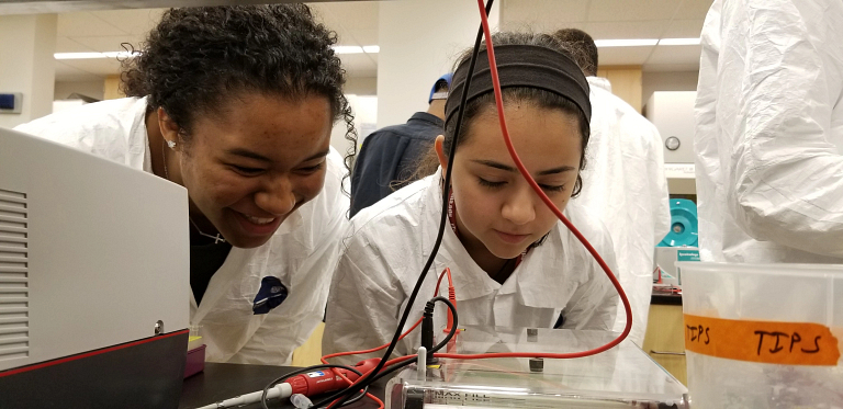 Two female students participate in a DNA analysis experiment
