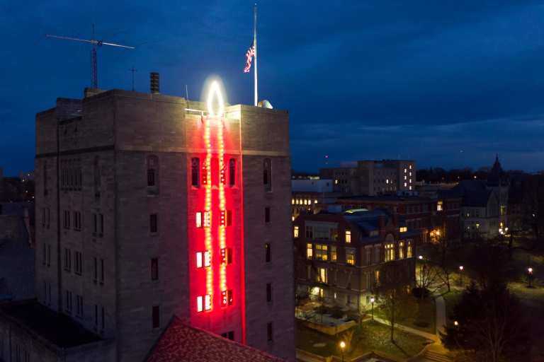 Red lights form a giant candle on the side of IU's union building