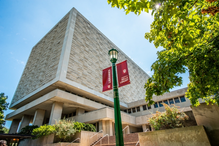 Two red banners on a light pole by the steps in front of the Herman B Wells Library