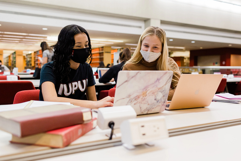 two students studying with laptops