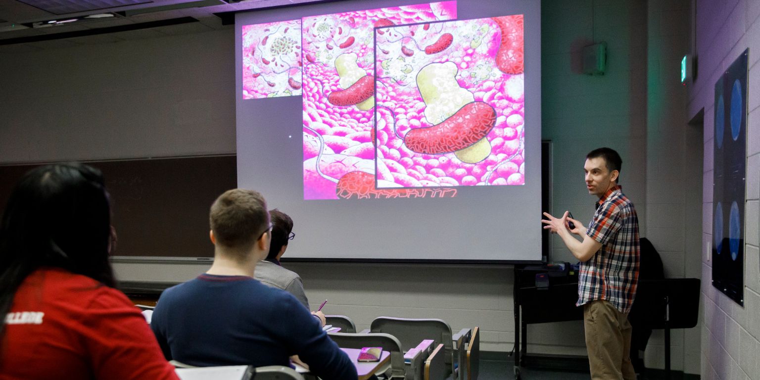 Professor Jake McKinlay teaching his microbial physiology course with his artwork.