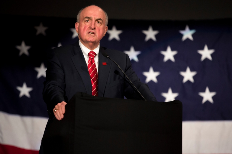 President Michael A. McRobbie speaks in front of a U.S. flag