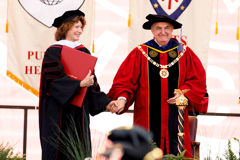 Michael A. McRobbie and Laurie Burns McRobbie on stage to receive honorary degrees. 