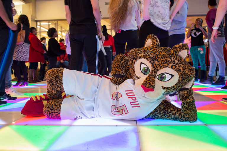 IUPUI mascot Jazzy lies on a multicolored lighted dance floor