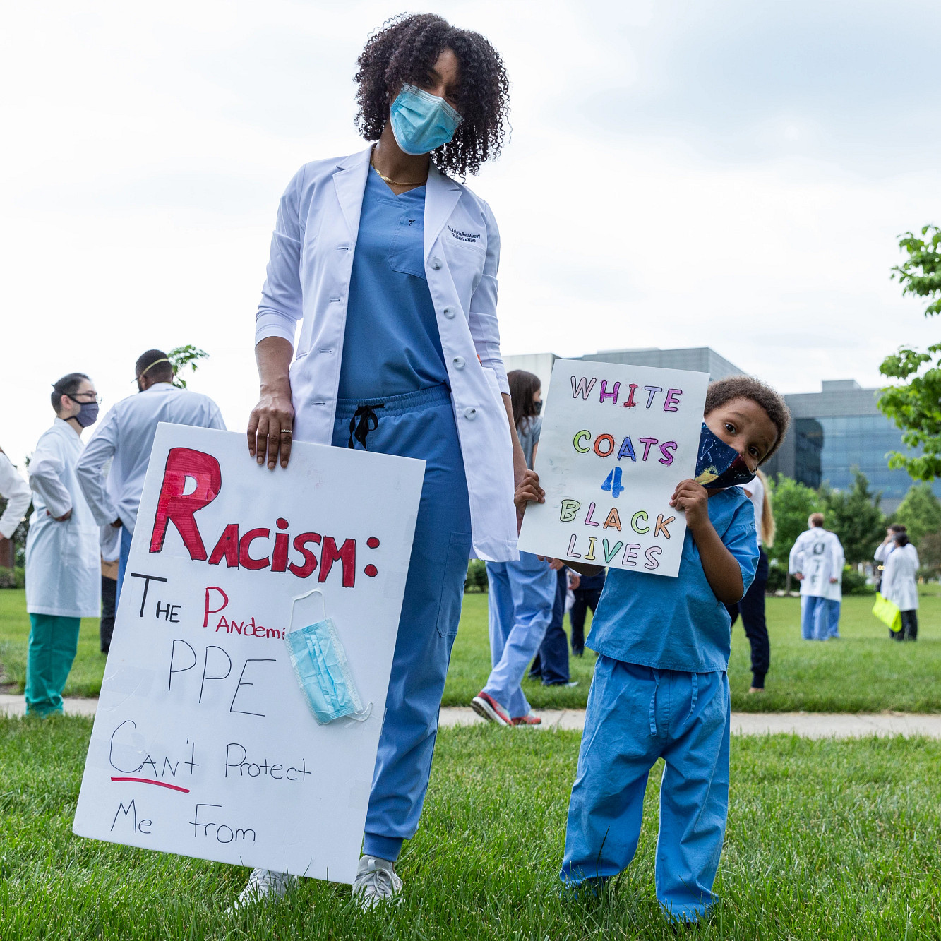 an adult and a child wearing masks hold signs supporting Black Lives Matter