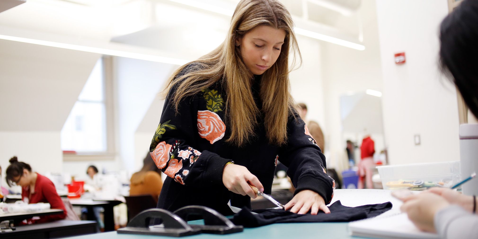 A fashion design student cuts fabric in class