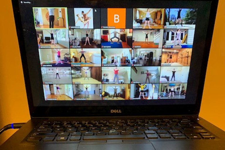 A laptop with a Zoom meeting displayed showing several ballet dancers during a technique class.