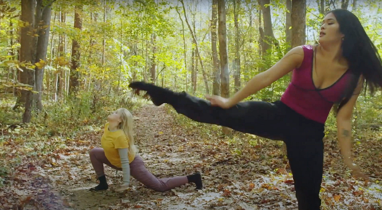 Two women dance in woods