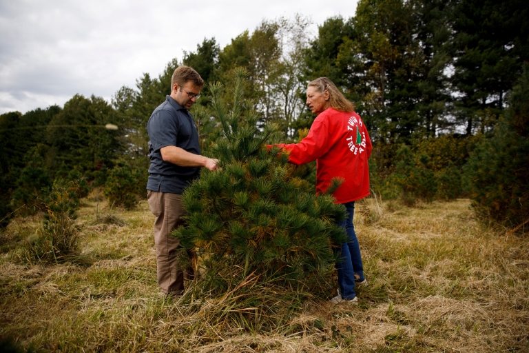 James Farmer and Jean Hopwood standing near an evergreen tree