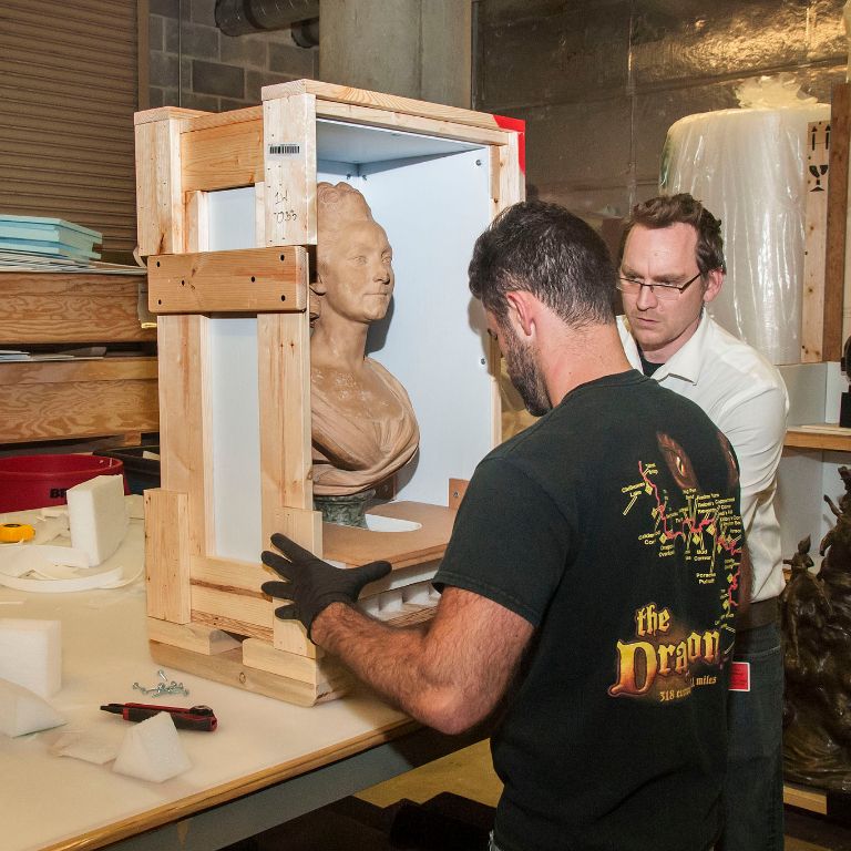 Two men load a single bust into a box at the Eskenazi Museum of Art 
