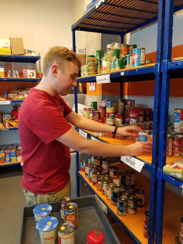 Michael Stottlemyer places canned foods on a shelf in the campus food pantry.