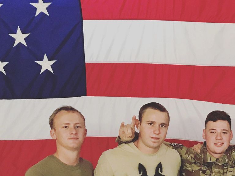 Seven U.S. Army soldiers stand in front of a large American flag