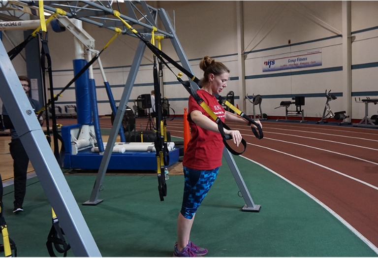 Woman performs suspension training exercises to work out.