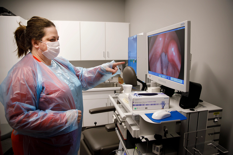 A woman looks at an image of vocal chords on a monitor in the voice clinic.