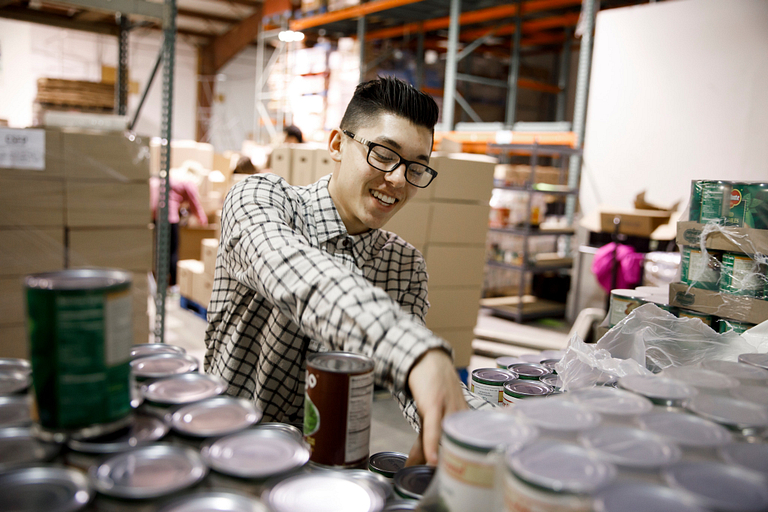 IU freshman Saleem Tucker stocks canned goods at the Hoosier Hills Food Bank