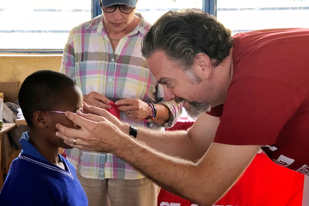 Don Lyon places glasses on a child. 