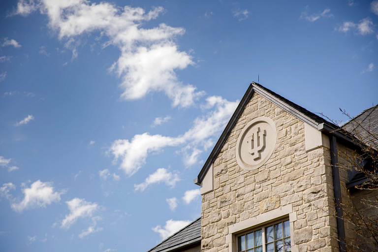 A limestone trident adorns the side of the Hutton Honors College on a spring day