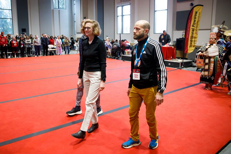 A woman and a man walk side by side in a large event space.