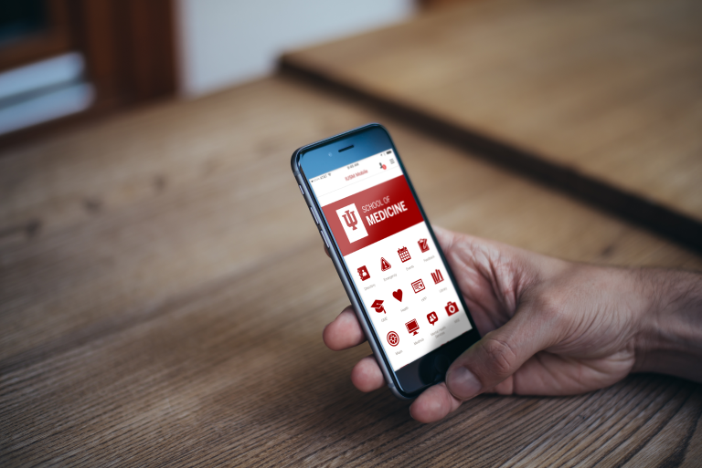 Hands hold a phone displaying the new IU School of Medicine app.
