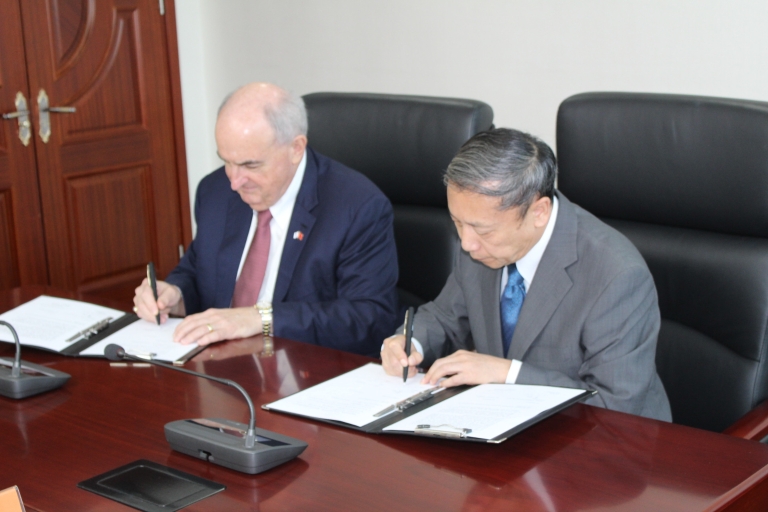 IU President McRobbie and Vice President Cai Fang lean over papers to sign