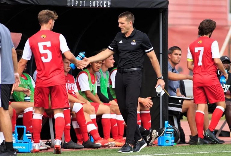 soccer coach high-fives his players on the sidelines of a game