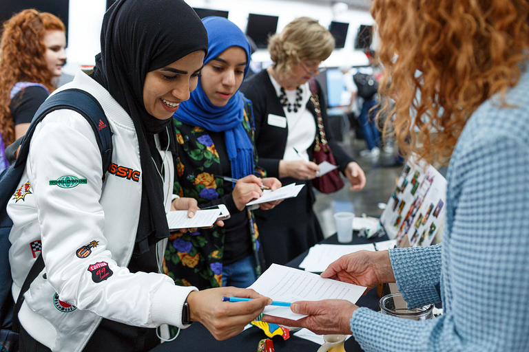 Two female students talking to a vendor at a booth