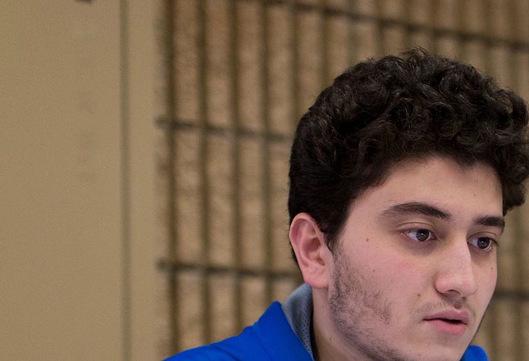 A male student in a blue sweatshirt looks at his laptop