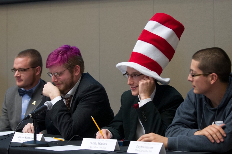 Four students at the Honors College Academic Bowl. One wears a large red and white hat.