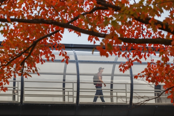 A student walks across a pedestrian bridge on the IUPUI campus