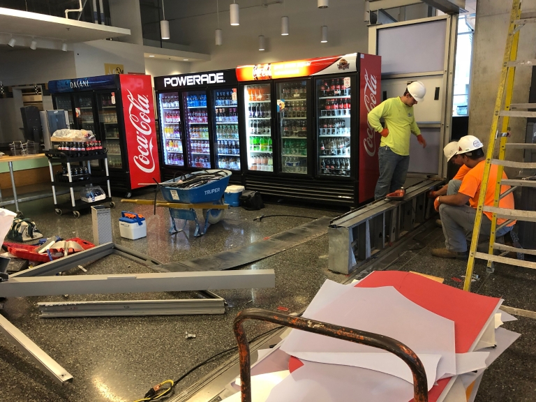 Construction workers clear out food court walls during renovations.