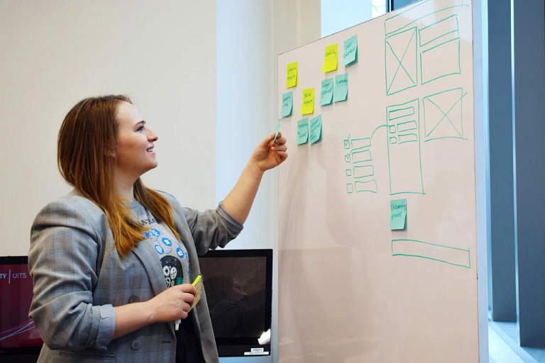 A female student places sticky notes on a board