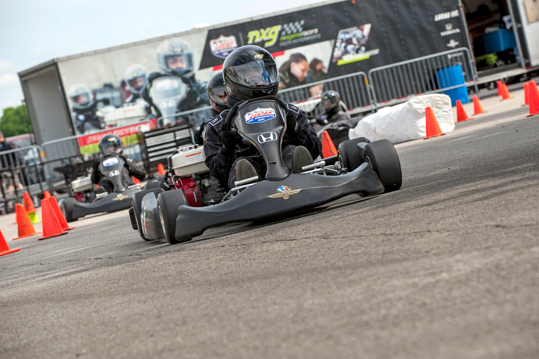 Youth driving a racecar-looking go-cart on a paved track.