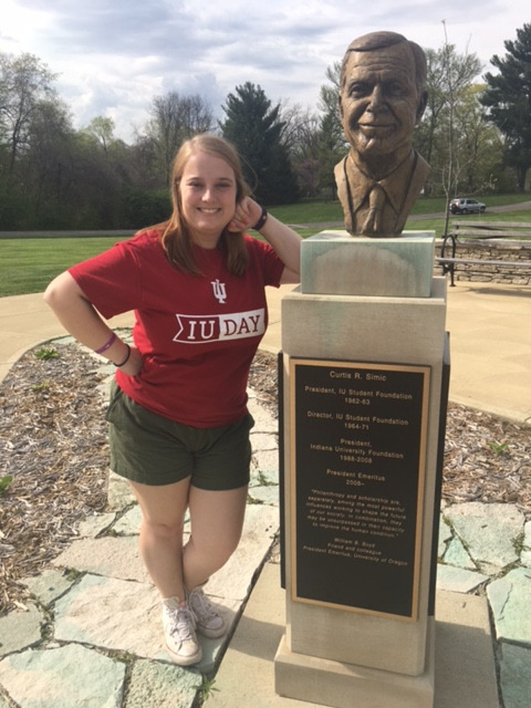 Libby Quigley poses next to a statue honoring Curtis R. Simic.