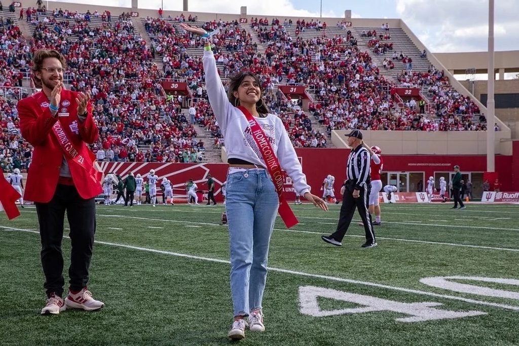 Daisy Trujillo waves to the crowd at a football game