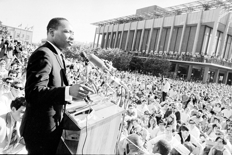 Man addresses crowd from podium