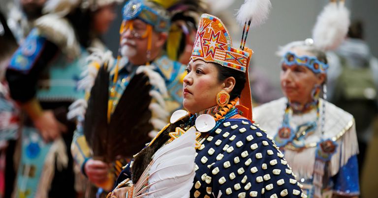 A woman in traditional powwow regalia performs a traditional dance.
