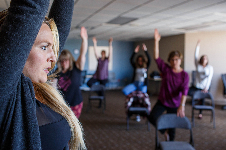 A group of faculty and staff participate in chair yoga on campus.