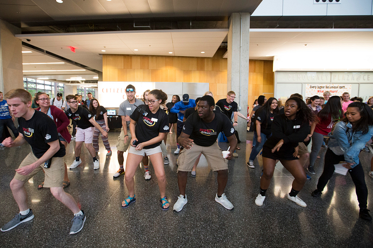 A group of students dance in the Campus Center building.