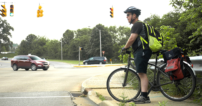 A man on his bicycle, waiting for a stoplight to change on a curb