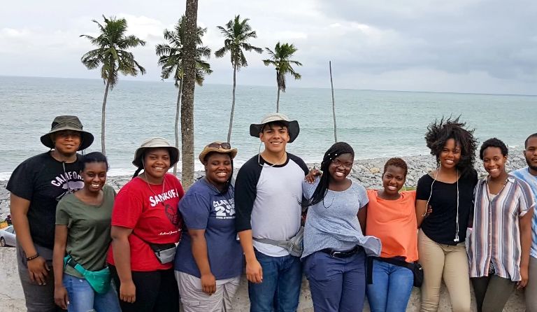 A group of students stand on a beach in Ghana