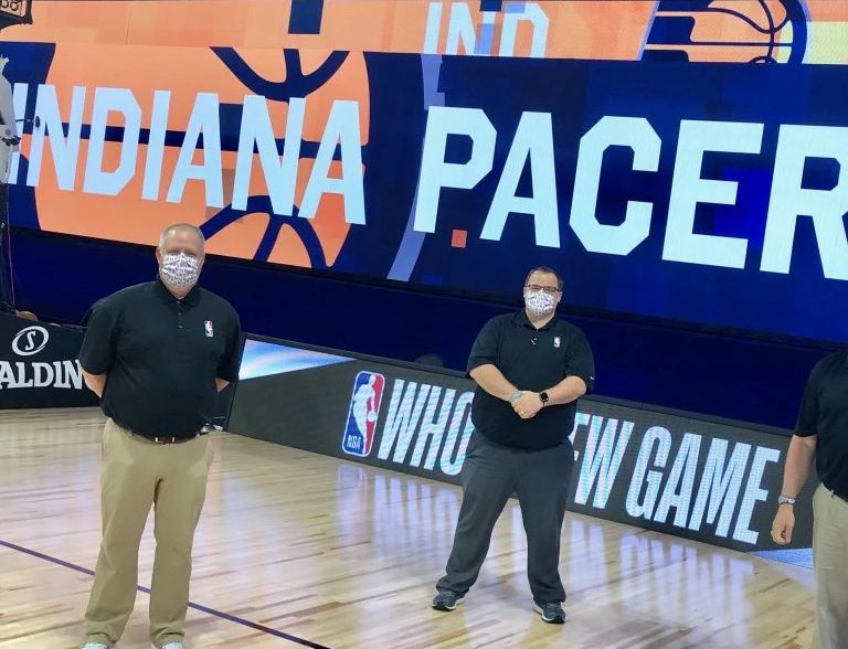 three people wearing masks standing on a basketball court