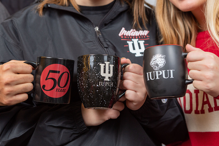 Students hold IUPUI coffee mugs.